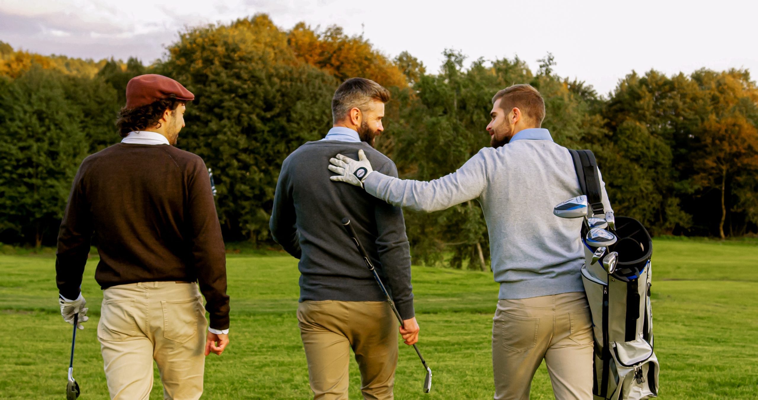 Three,Male,Friends,With,Clubs,And,Golf,Bag,Walking,On